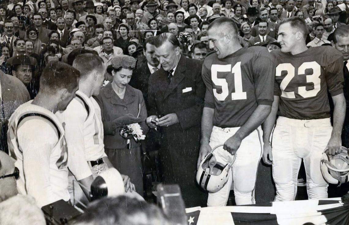 Queen Elizabeth II and Maryland Gov. Theodore R. McKeldin (R) examine the ceremonial coin as captains from North Carolina, left, and Maryland look on.