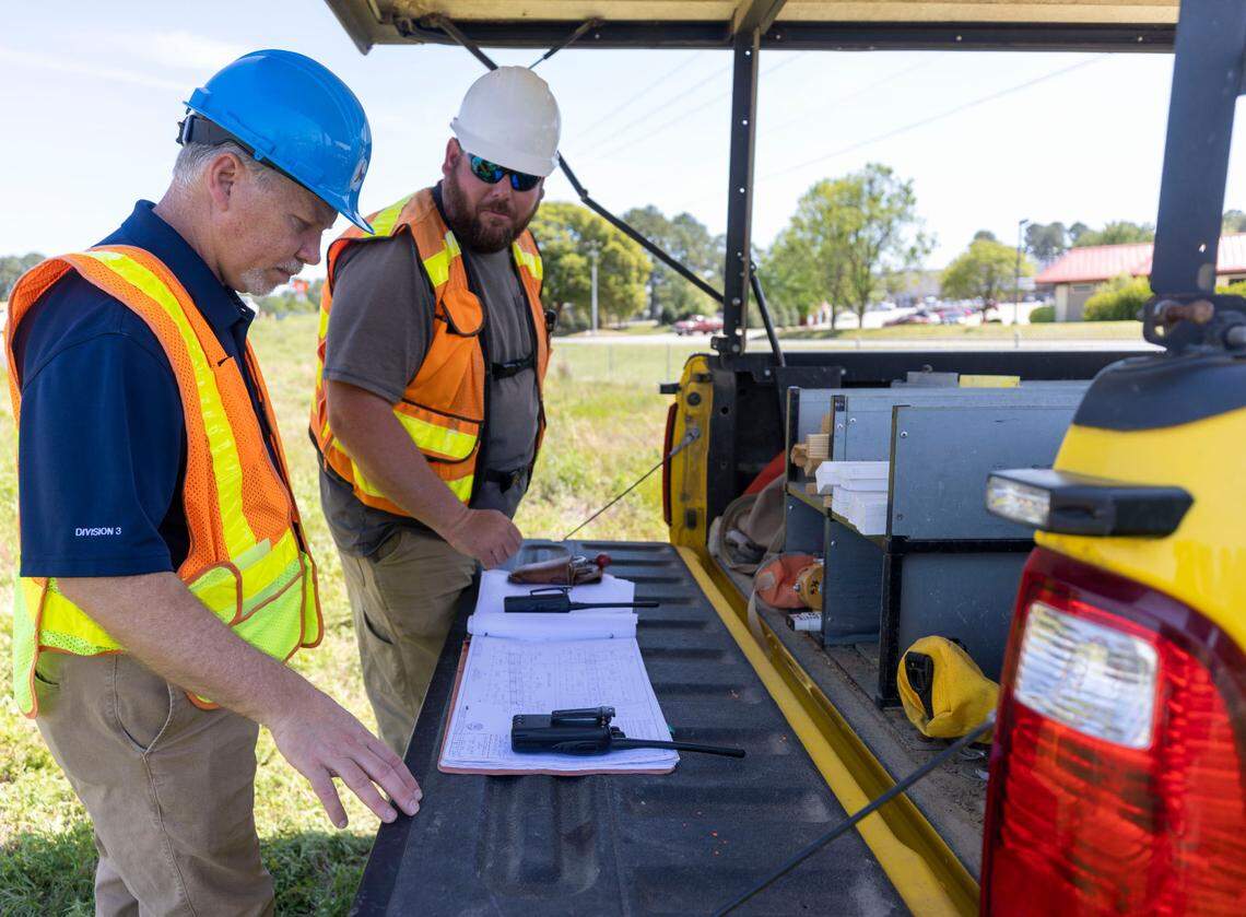 NCDOT district engineer Dan Cumbo, left, inspects survey plans for a new bridge with engineering technician John Peede on Wednesday, April 13, 202 in Clinton, N.C.