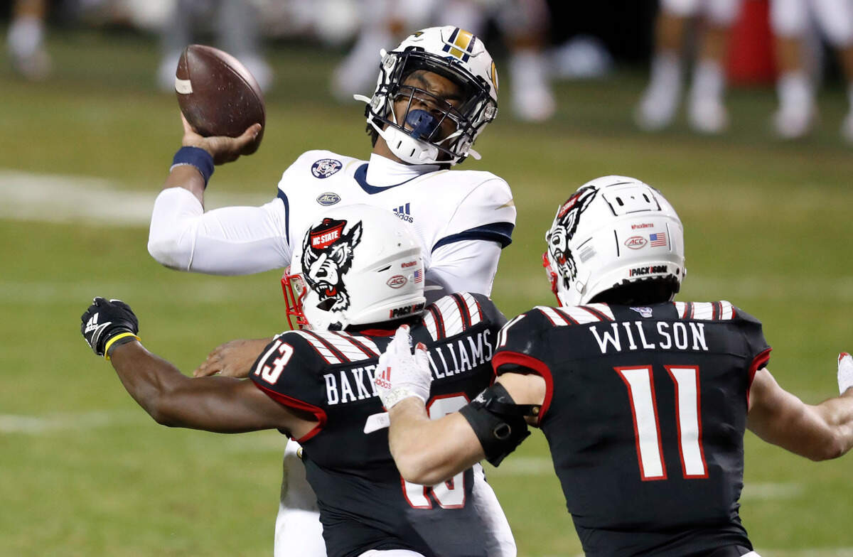 Georgia Tech quarterback Jeff Sims (10) throws as he is hit by N.C. State defensive back Tyler Baker-Williams (13) during the first half of N.C. State’s game against Georgia Tech at Carter-Finley Stadium in Raleigh, N.C., Saturday, Dec. 5, 2020. N.C. State linebacker Payton Wilson (11) also pressures Sims