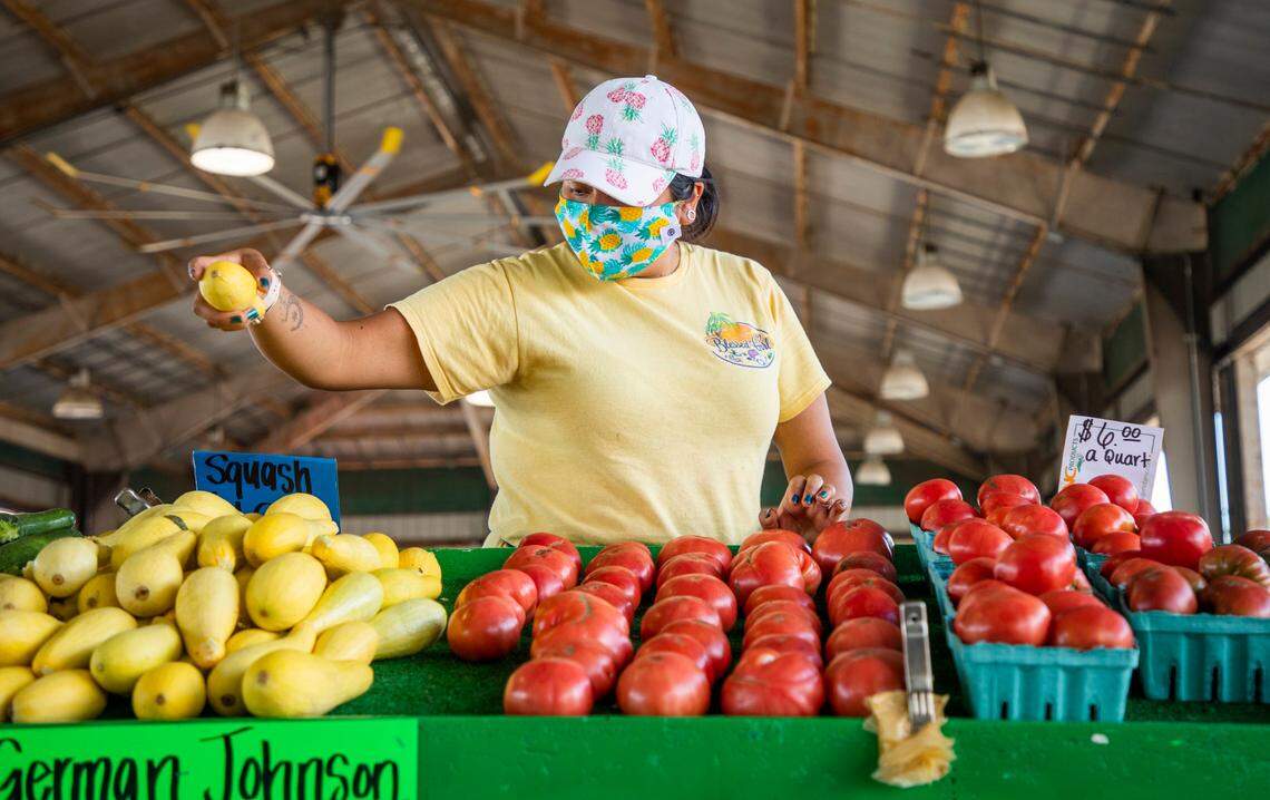 Leticia Seras organizes squash for sale at the Penny’s Produce stand at the North Carolina State Farmers Public Market on Tuesday, July 28, 2020, in Raleigh, N.C.