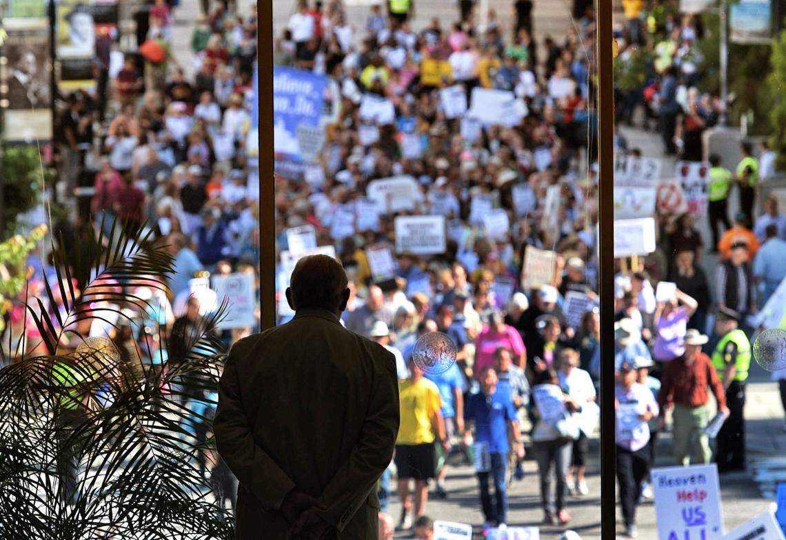 A member of the N.C. General Assembly Sgt. at Arms watches as members of the Moral Monday cross the street towards the legislative building Monday, May 16, 2016. Hundreds of protesters convened on the General Assembly to protest controversial HB2.