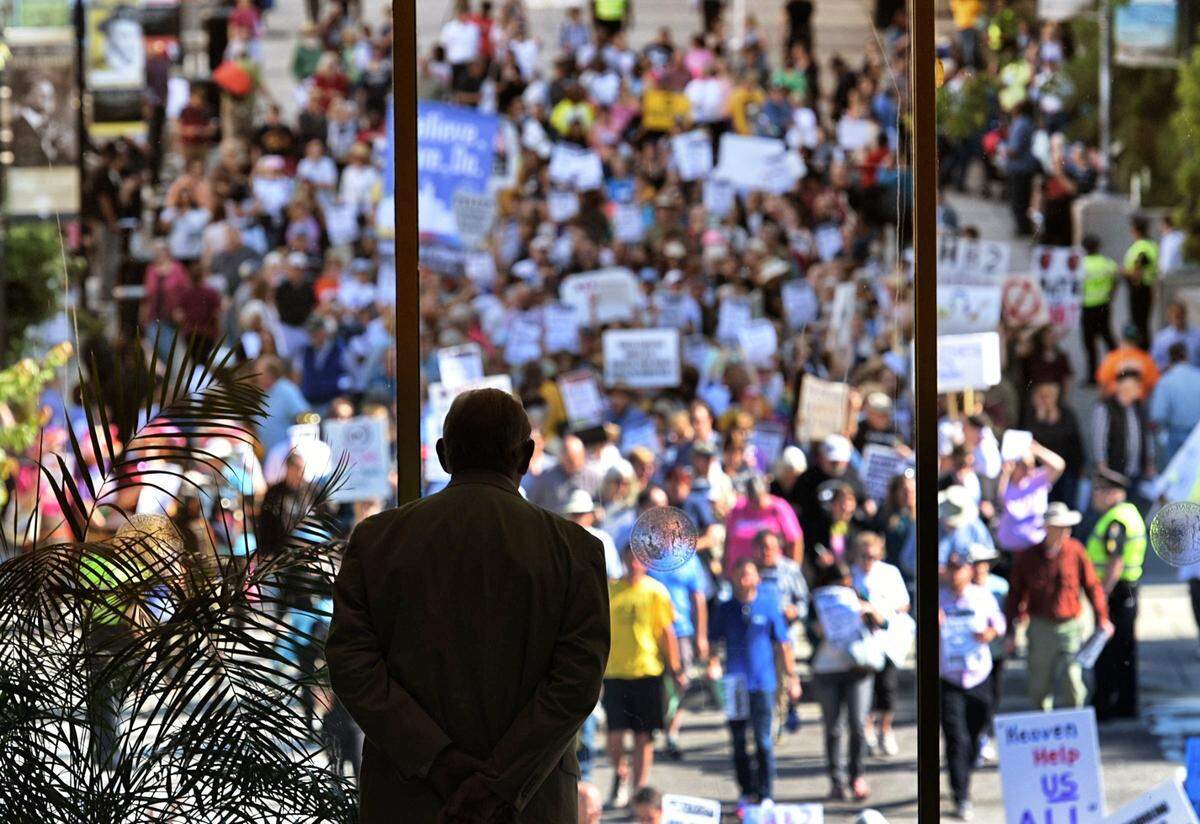 A member of the N.C. General Assembly Sgt. at Arms watches as members of the Moral Monday cross the street towards the legislative building Monday, May 16, 2016. Hundreds of protesters convened on the General Assembly to protest controversial HB2.