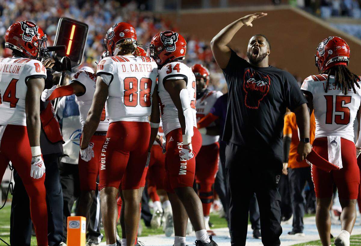 N.C. State’s Grant Gibson, right, celebrates along with teammates after wide receiver Devin Carter (88) made a 26-yard touchdown reception during the second half of N.C. State’s 30-27 overtime victory over UNC at Kenan Stadium in Chapel Hill, N.C., Friday, Nov. 25, 2022.