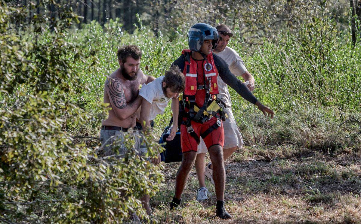 Reece Williams, center right, a swimmer with the U.S. Coast Guard, helps carry a 17-year-old to a helicopter that will take him to an ambulance, in Burgaw, N.C., Sept. 18, 2018. 