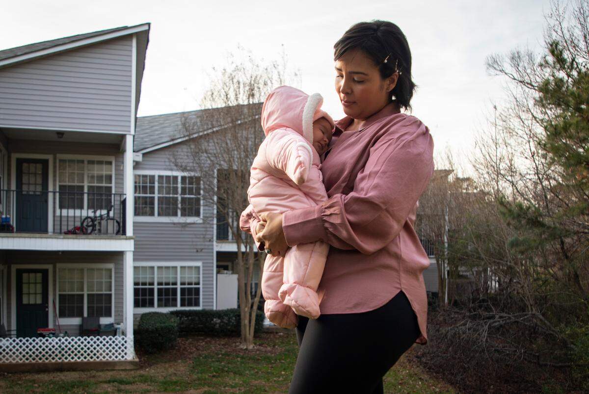 Erika White, a renter living in an apartment in Cary, N.C., poses for a portrait while holding her two-month-old daughter Amba on Dec. 20, 2021.