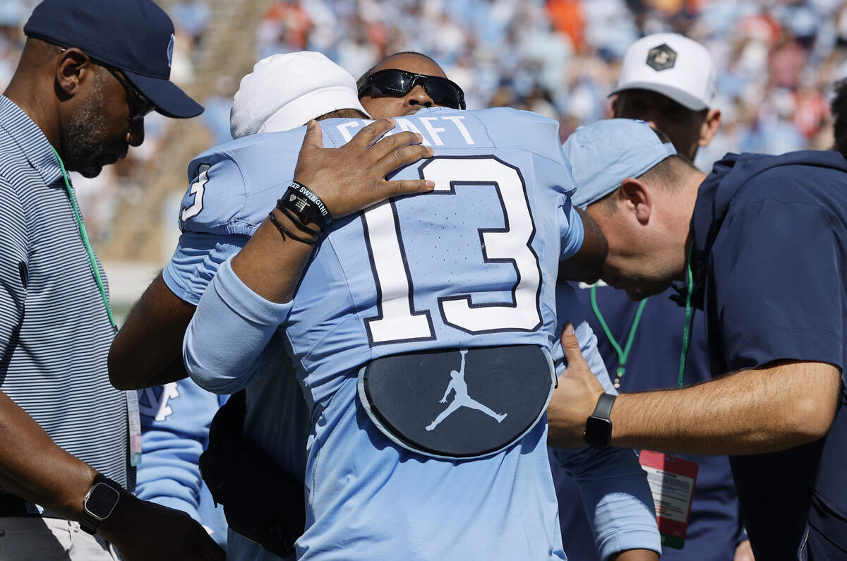 Mitch Mason, North Carolina football’s chaplain, is hugged by North Carolina wide receiver Jordan Shipp (13) during a ceremony honoring Mason in  the first half of UNC’s game against Clemson at Kenan Stadium in Chapel Hill, N.C., Sat. Oct. 4, 2025.