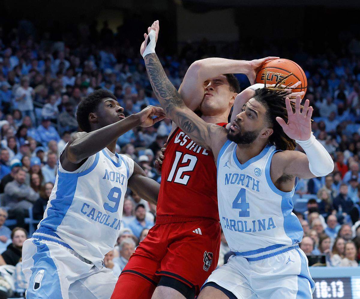 N.C. State’s Michael O’Connell drives to the basket against North Carolina’s Drake Powell and RJ Davis during the second half of the Wolfpack’s 97-73 loss on Wednesday, Feb. 19, 2025, at the Smith Center in Chapel Hill, N.C.