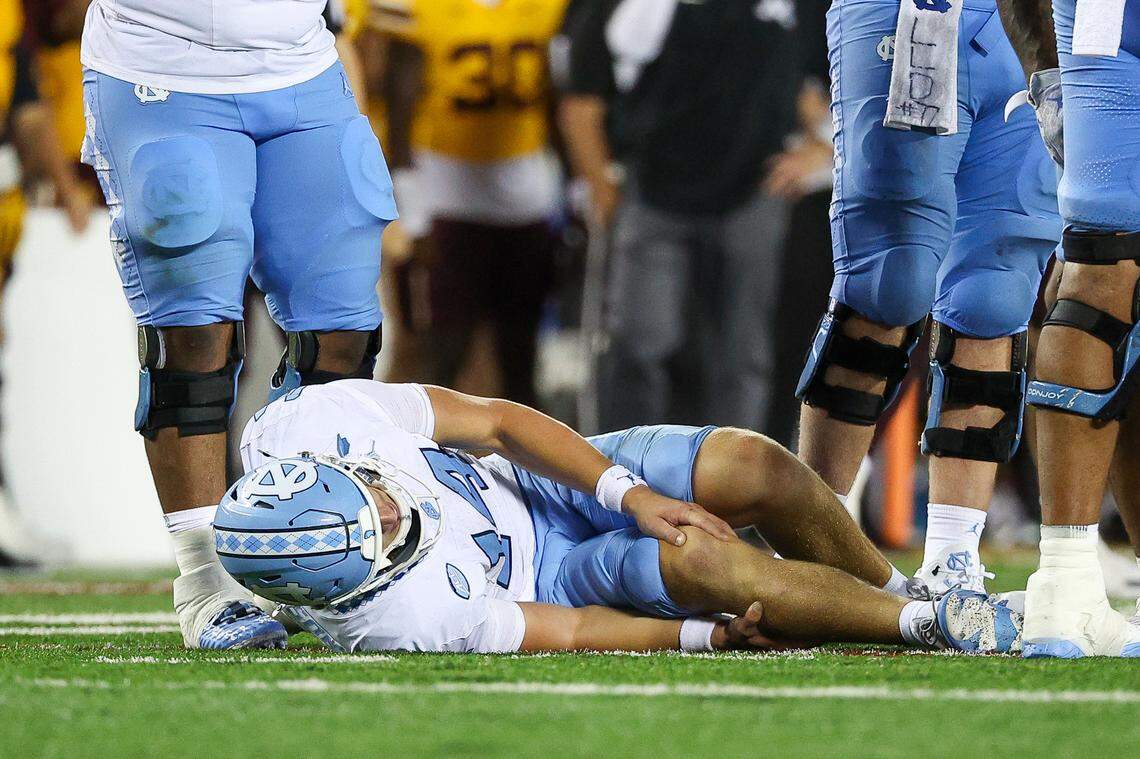 Aug 29, 2024; Minneapolis, Minnesota, USA; North Carolina Tar Heels quarterback Max Johnson (14) grabs his knee after being tackled during the second half against the Minnesota Golden Gophers at Huntington Bank Stadium. Mandatory Credit: Matt Krohn-USA TODAY Sports