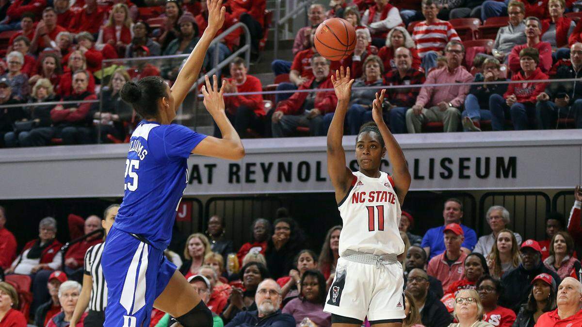 N.C. State guard Kiara Leslie attempts a corner three over Duke center Jade Williams during their January 3, 2019 game at Reynolds Coliseum in Raleigh. The Wolfpack defeated the Blue Devils 63-51 for their 14th consecutive victory, which at the time tied their best start to a season in program history.