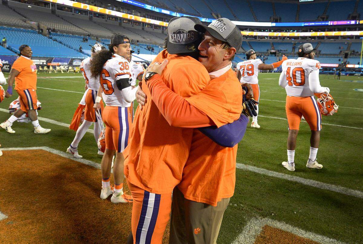 Clemson Tigers head coach Dabo Swinney, right, hugs a player following the teamÕs victory in the ACC Championship game. Clemson defeated Notre Dame 34-10 to win the championship at Bank of America Stadium in Charlotte, NC on Saturday, December 19, 2020.