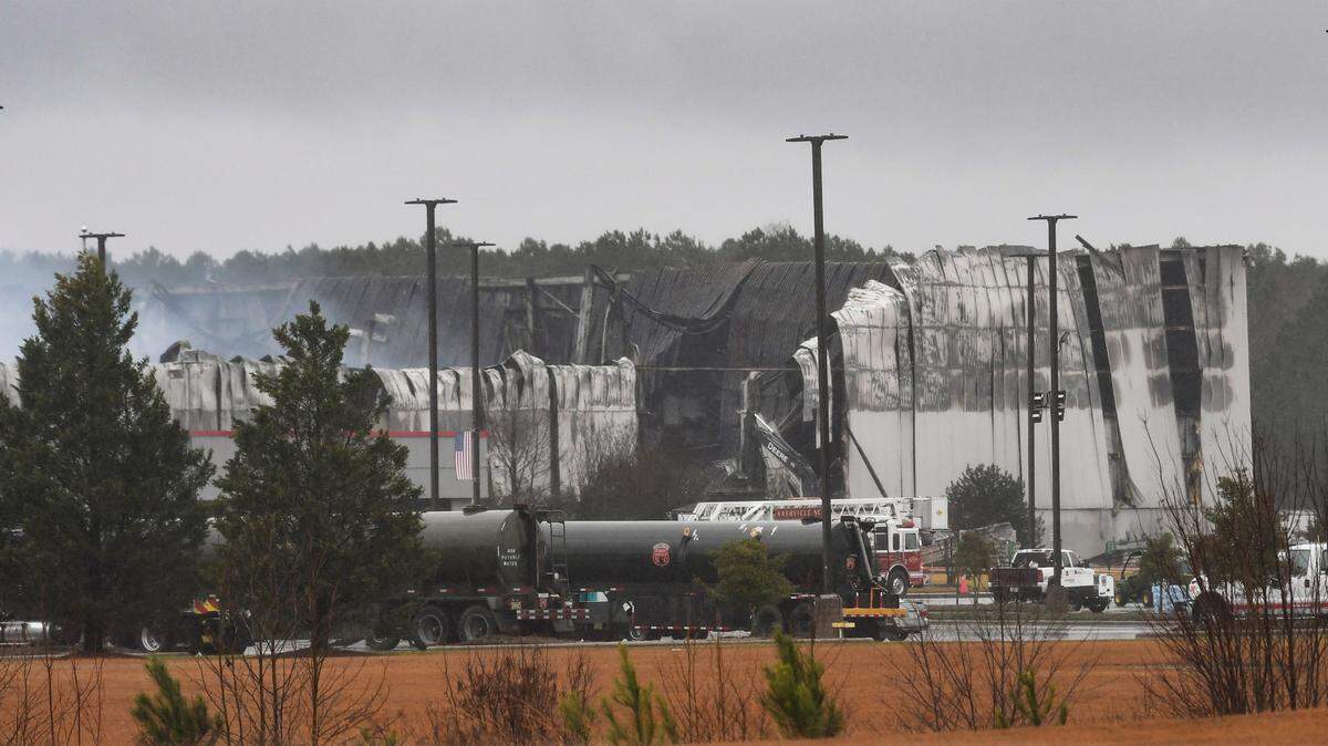 Smoke rises from gutted areas of the QVC shipping facility in Rocky Mount, N.C. Sunday morning, Dec. 19, 2021 as firefighters continue to spray water into hot spots.