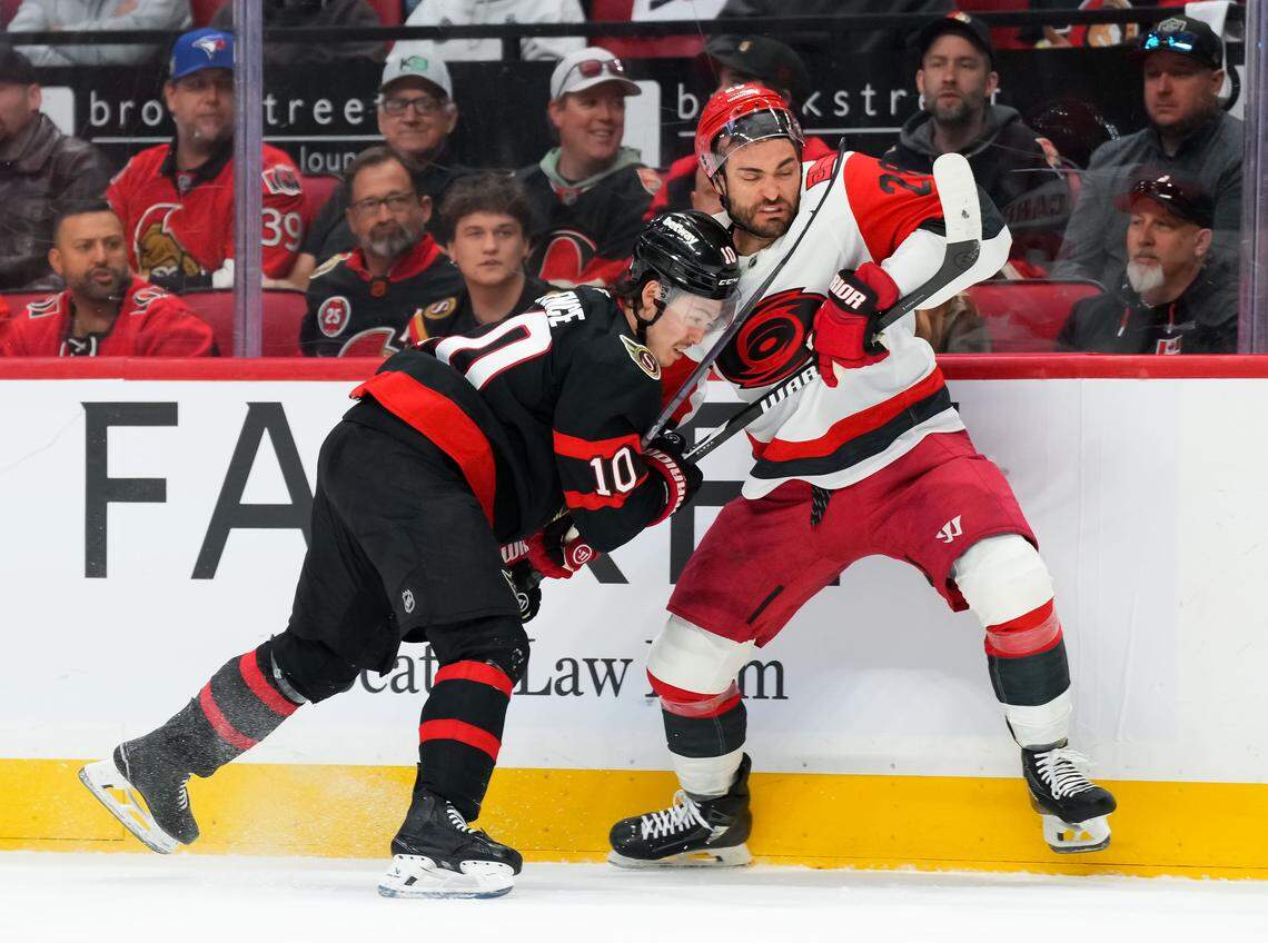 Jordan Spence, left, of the Ottawa Senators checks William Carrier of the Carolina Hurricanes during the first period in Game 4 of the first round of the 2026 Stanley Cup Playoffs at Canadian Tire Centre on April 25, 2026 in Ottawa, Canada.