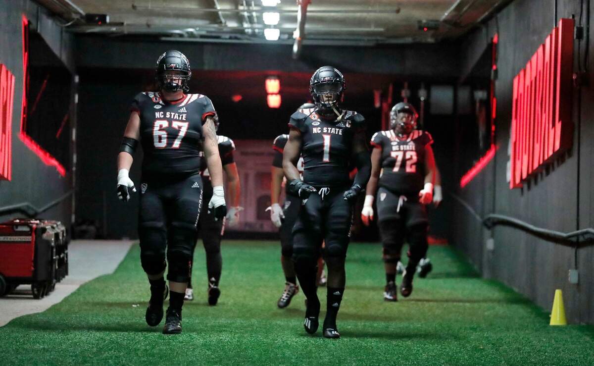 N.C. State offensive tackle Justin Witt (67) and linebacker Isaiah Moore (1) walk down towards the field to warmups before N.C. State’s game against Miami at Carter-Finley Stadium in Raleigh, N.C., Friday, Nov. 6, 2020.