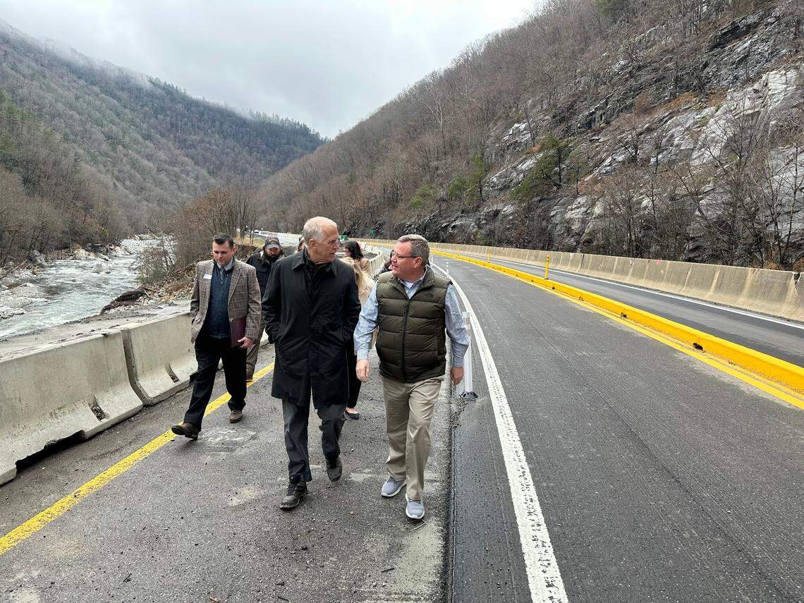 U.S. Sen. Thom Tillis and U.S. Rep. Tim Moore walk along Interstate 40 in the Pigeon River Gorge on Monday, Feb. 10, 2025. To the right are the westbound lanes of the highway, which are scheduled to open to two-way traffic, with the yellow concrete median, on March 1.
