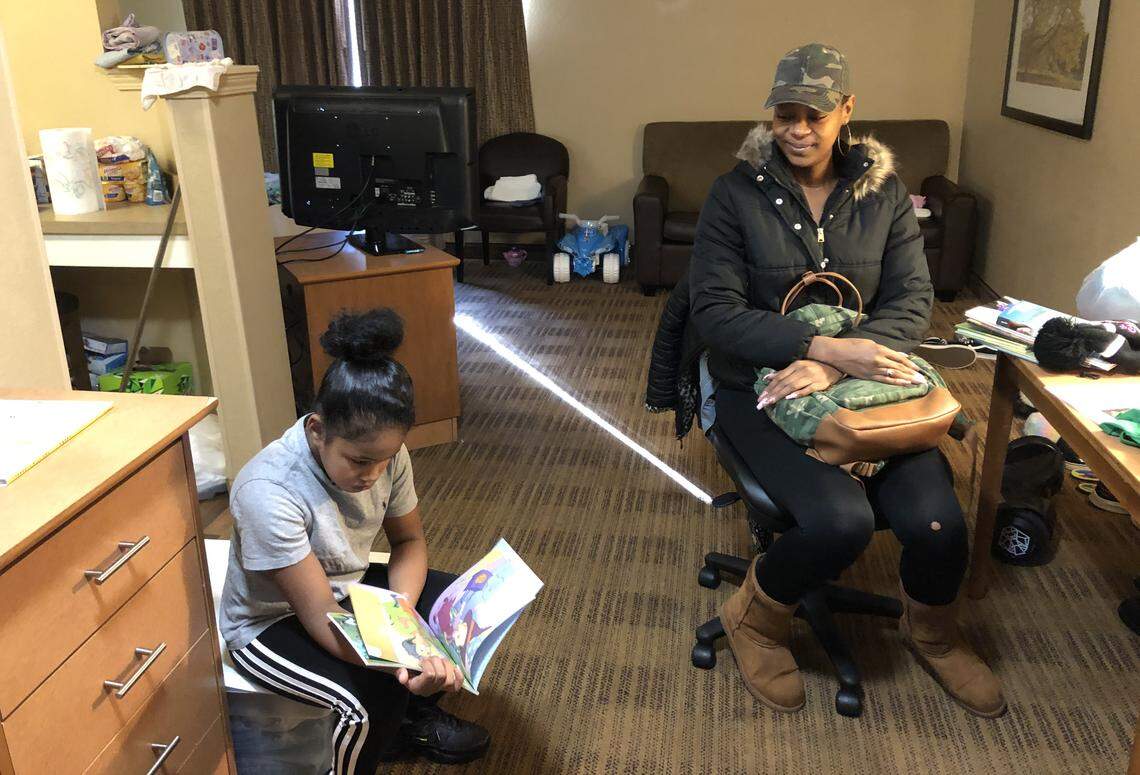 Rateakka Johnson, right, listens as her daughter, Samantha, reads a book in the hotel room where they have stayed for nearly three weeks since being evacuated from McDougald Terrace because of carbon monoxide. 