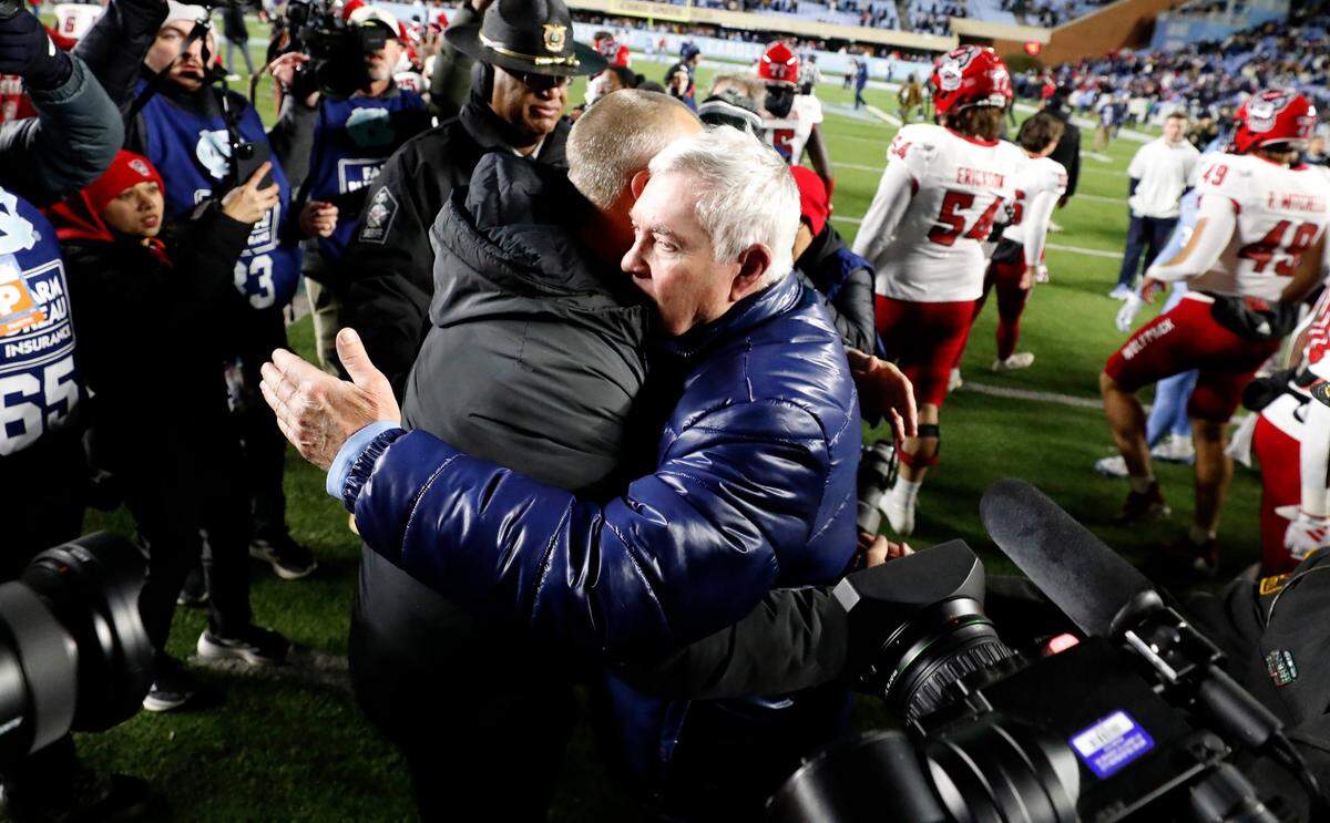North Carolina head coach Mack Brown hugs N.C. State head coach Dave Doeren after N.C. State’s 35-30 victory over UNC at Kenan Stadium in Chapel Hill, N.C., Saturday, Nov. 30, 2024.