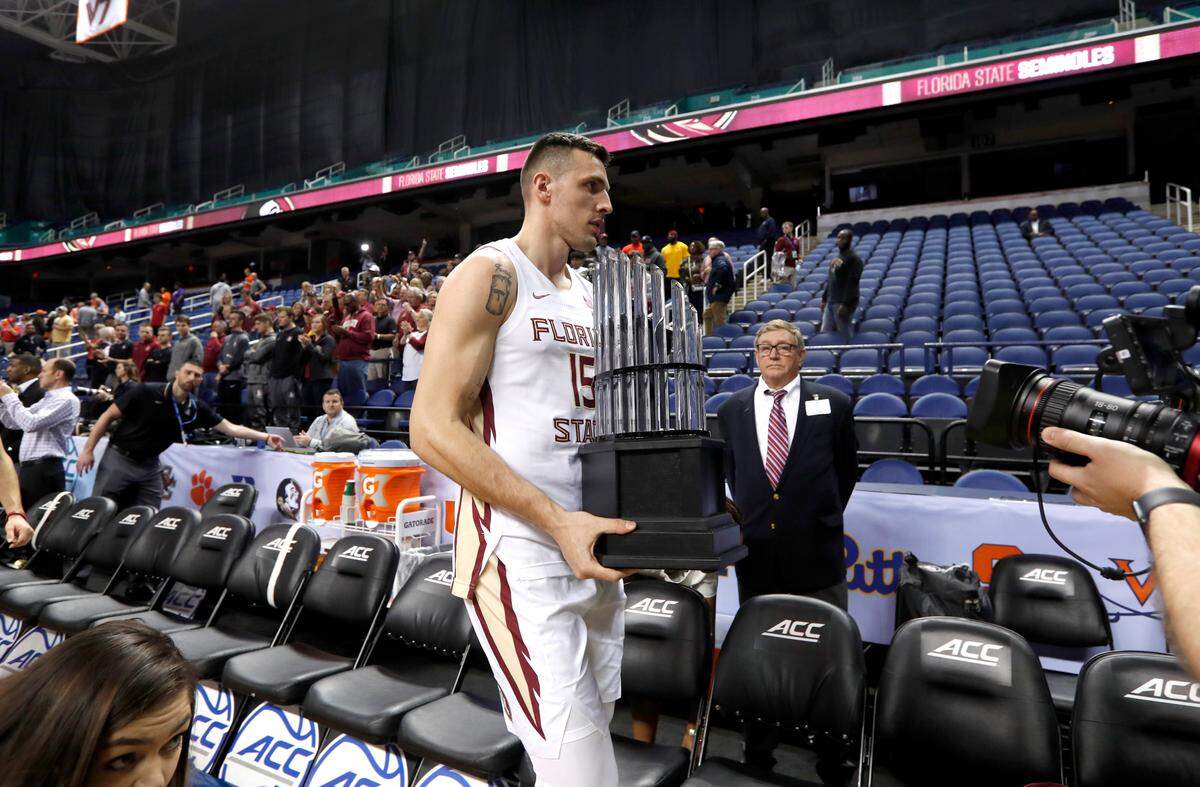 Florida State’s Dominik Olejniczak walks off the floor with the ACC championship trophy at the Greensboro Coliseum Thursday, March 12, 2020, after it was announced the ACC basketball tournament had been canceled amid rapidly increasing concerns about the spread of COVID-19, the coronavirus disease.