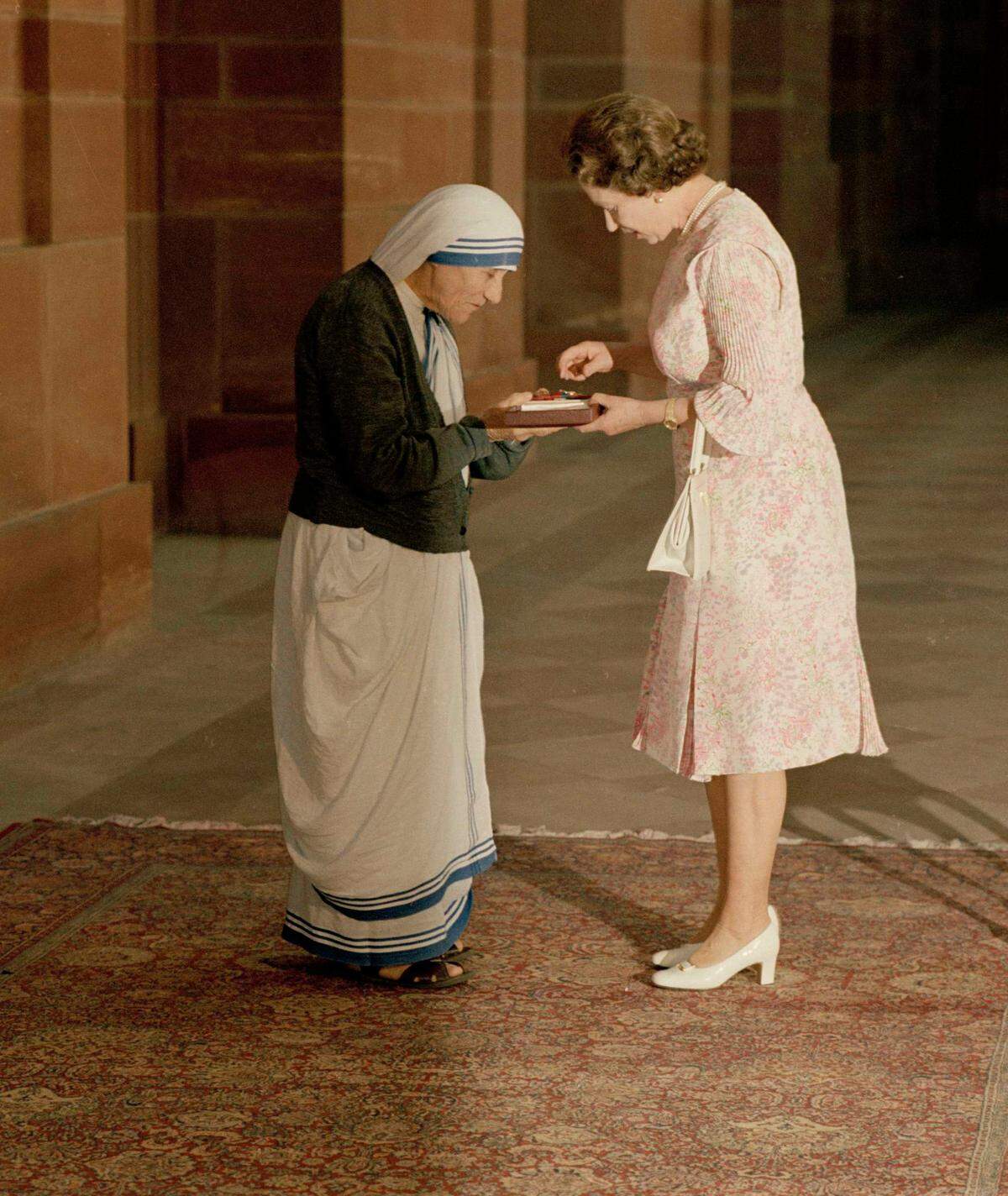 With heads bowed, the Queen and Mother Teresa look at the Insignia of the Honorary Order of Merit which Her majesty has just presented to the Lady of Calcutta, at the Rashtrapati Shavar, in New Delhi, Thursday, November 24, 1983.