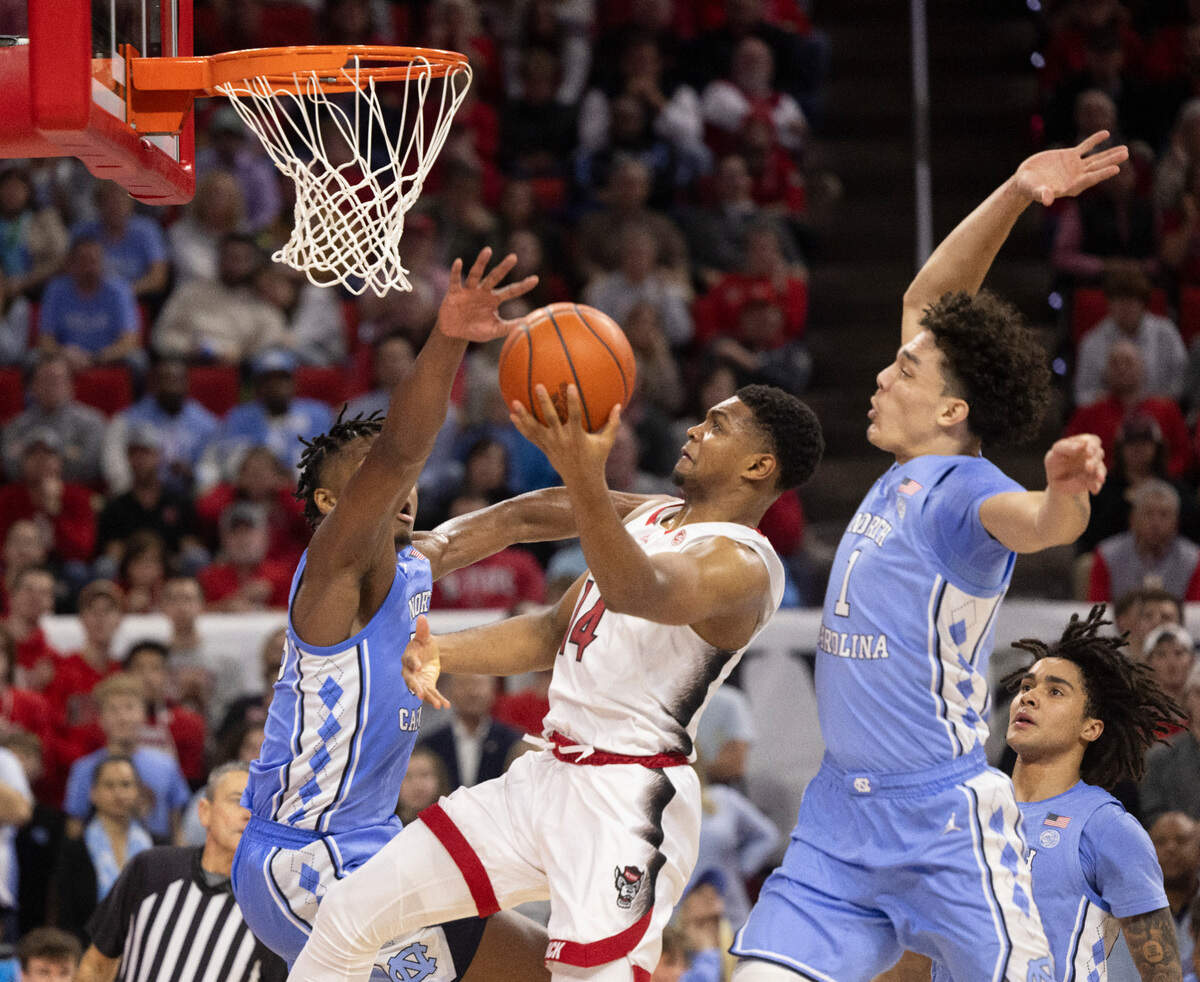 N.C. State’s Casey Morsell (14) drives to the basket against North Carolina’s Harrison Ingram (55) and Zayden High (1) in the first half on Wednesday, January 10, 2024 at PNC Arena in Raleigh, N.C