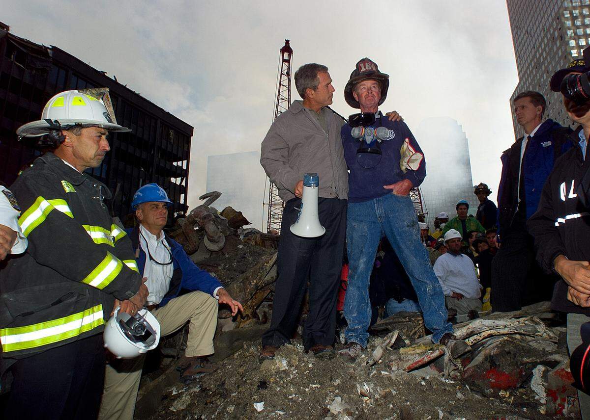 As rescue efforts continue in the rubble of the World Trade Center in New York, President Bush stands with firefighter Bob Beckwith on a burnt fire truck in front of the World Trade Center during a tour of the devastation, Friday, Sept. 14, 2001.