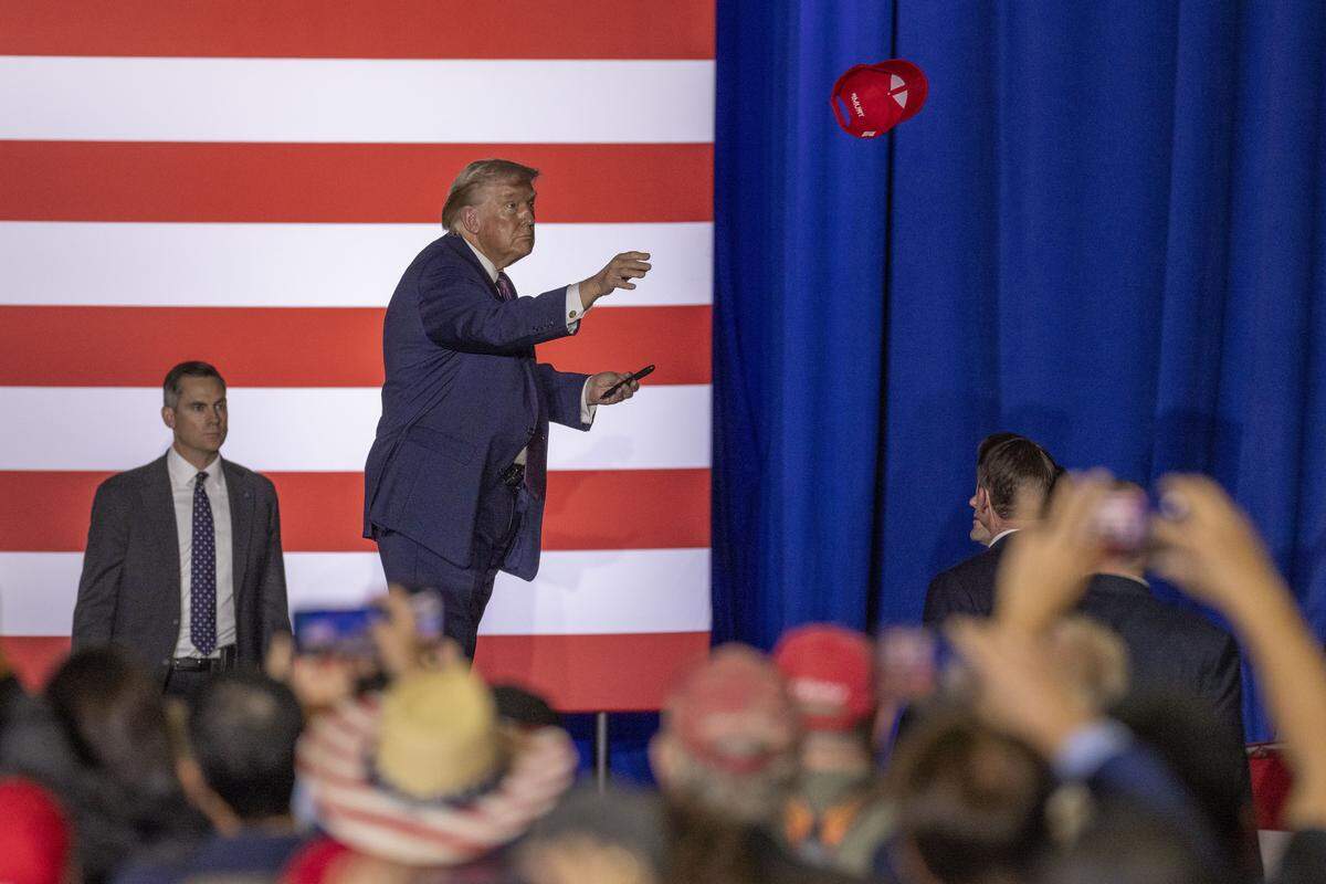 President Donald Trump tosses an autographed red Make America Great Again hat into the crowd during a rally at the Rocky Mount Event Center in Rocky Mount on Friday, Dec. 19, 2025.