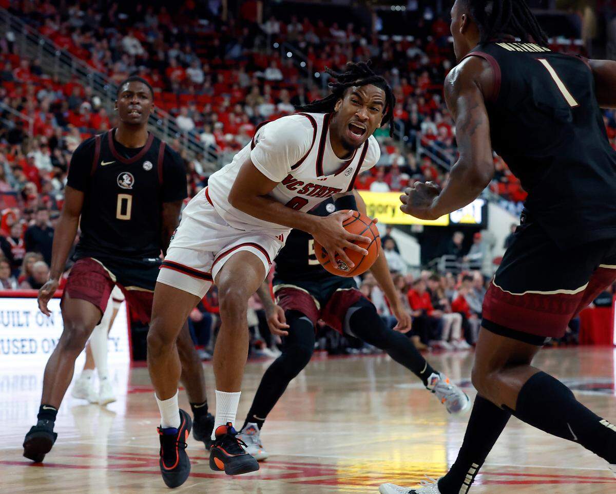 N.C. State’s Jayden Taylor drives to the basket past Florida State’s Chandler Jackson and Jamir Watkins during the second half of the Wolfpack’s 84-74 overtime victory on Saturday, Dec. 7, 2024, at Lenovo Center in Raleigh, N.C.