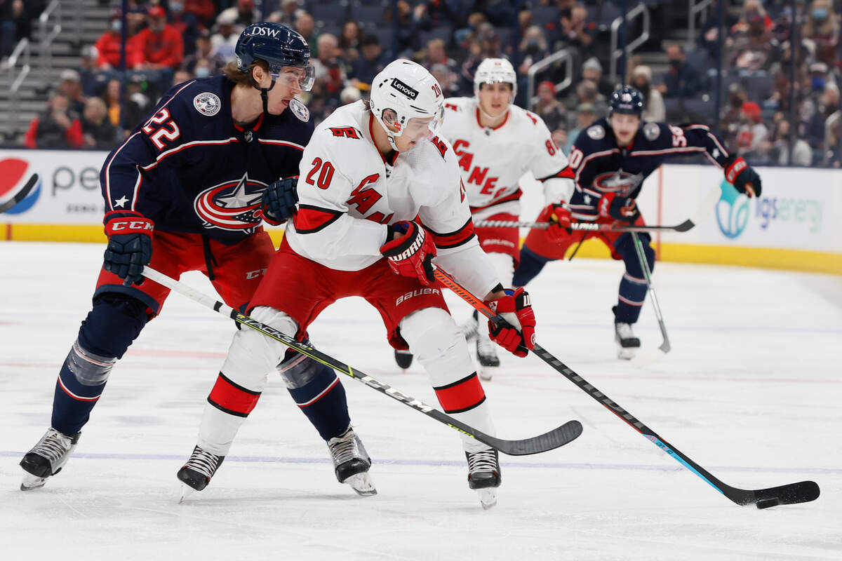 Carolina Hurricanes’ Sebastian Aho, right, carries the puck across the blue line as Columbus Blue Jackets’ Jake Bean defends during the first period of an NHL hockey game Saturday, Jan. 1, 2022, in Columbus, Ohio. (AP Photo/Jay LaPrete)