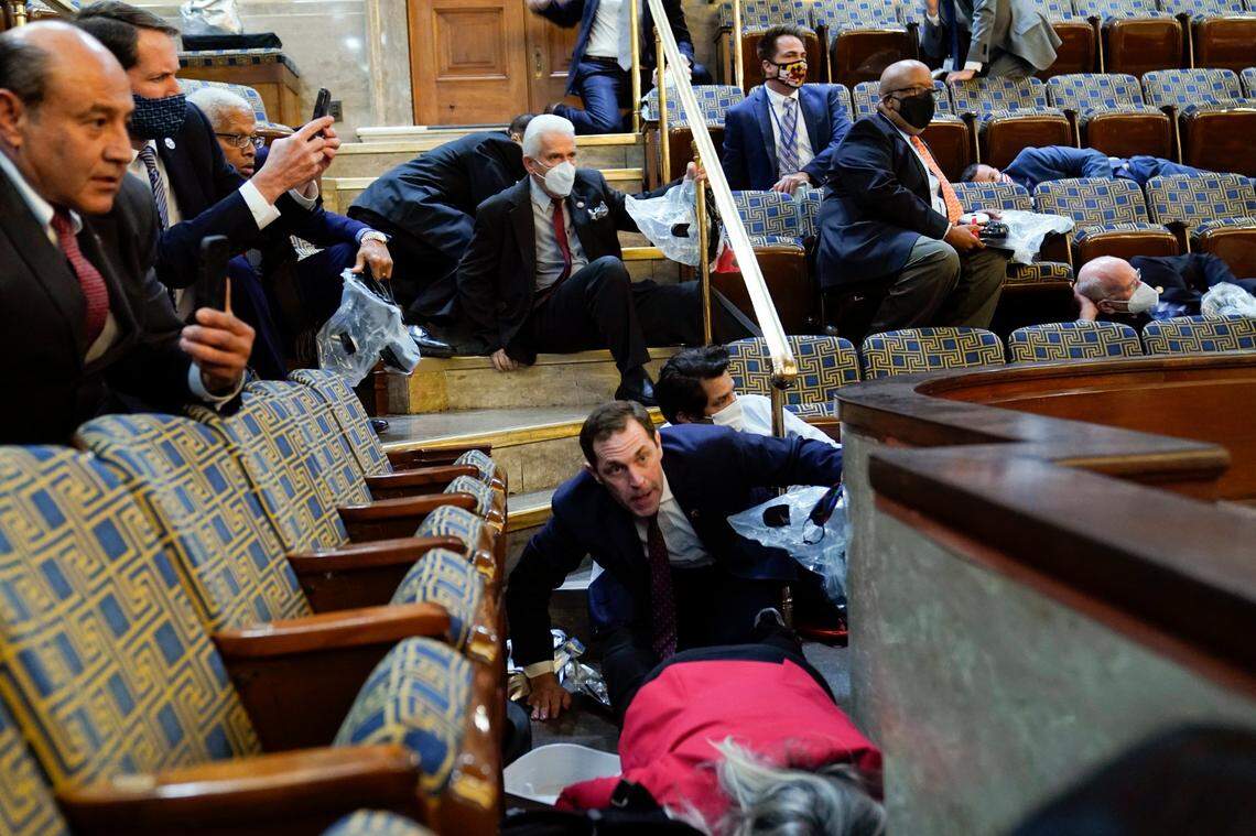 People shelter in the House gallery as rioters try to break into the House Chamber at the U.S. Capitol on Wednesday, Jan. 6, 2021, in Washington.