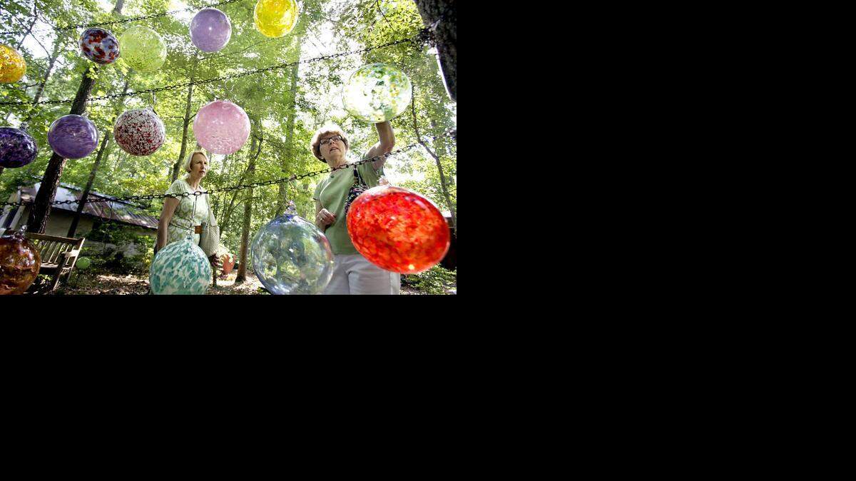 Friends Carolyn Long, left, and Mary Covington, both of Mebane, admire garden globes by Raleigh artist Lisa Oakley along the wooded pathways at the Cedar Creek Gallery they frequent in Creedmoor on Wednesday.

