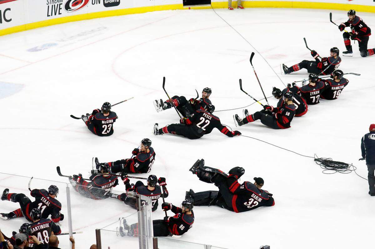 The Carolina Hurricanes’ team slides down the ice in celebration after defeating the San Jose Sharks in Raleigh, N.C. Friday, Oct. 26, 2018. 