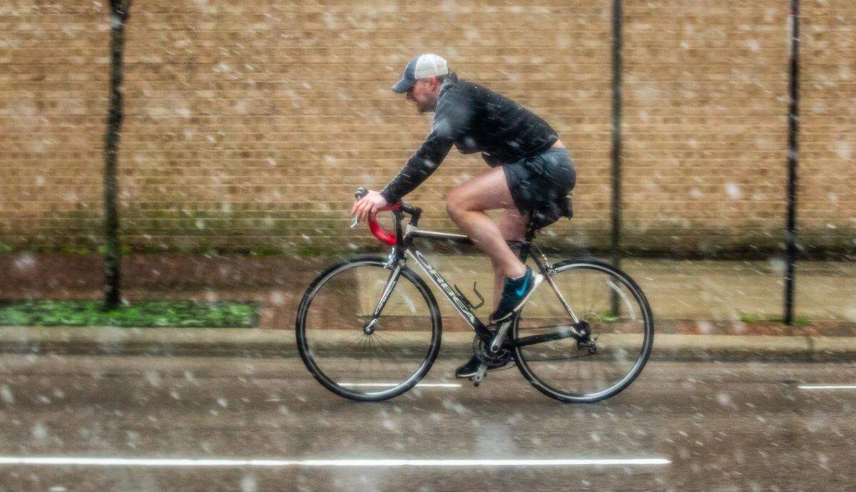 A cyclist seems unfazed as he rides wearing shorts while snow falls on Wilmington Street in downtown Raleigh Thursday, afternoon Feb. 20, 2020.