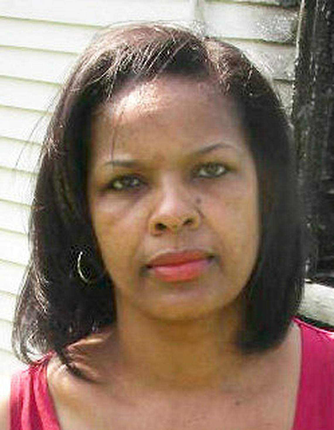 Rich Square native Shelia Moses, photographed in 2011, holds a portrait of her brother, Daniel, outside the burned remains of the family house. She has used the house as a centerpiece to her young adult fiction.