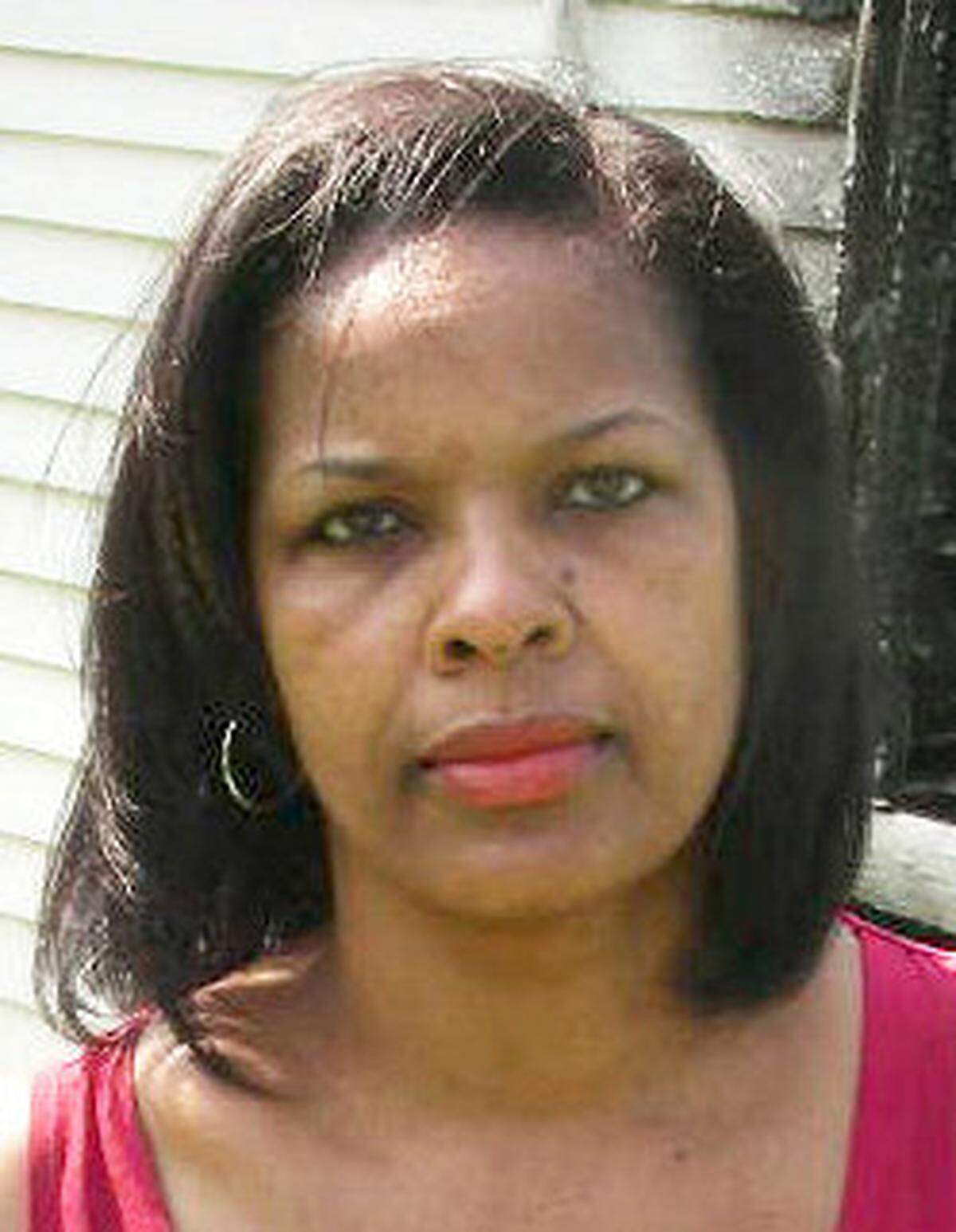 Rich Square native Shelia Moses, photographed in 2011, holds a portrait of her brother, Daniel, outside the burned remains of the family house. She has used the house as a centerpiece to her young adult fiction.