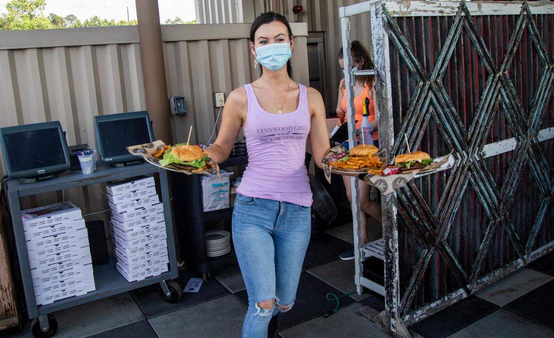 Server Stephanie Hurley delivers an order to a table at Lynnwood Brewing Concerns Grove Barton Road location Friday, May 22, 2020. North Carolina entered Phase Two of its reopening plan Friday, allowing restaurants and personal care services to open at 50% capacity.