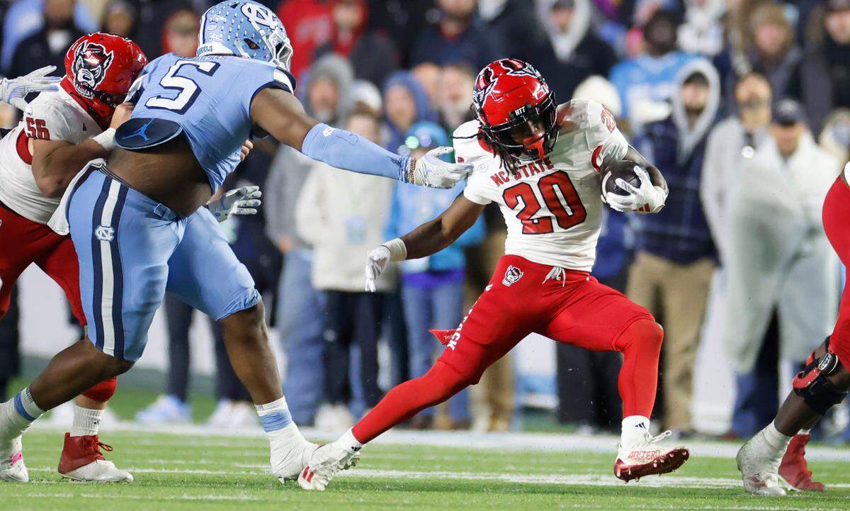 N.C. State running back Hollywood Smothers (20) breaks away from North Carolina defensive lineman Jahvaree Ritzie (5) during the second half of N.C. State’s 35-30 victory over UNC at Kenan Stadium in Chapel Hill, N.C., Saturday, Nov. 30, 2024.