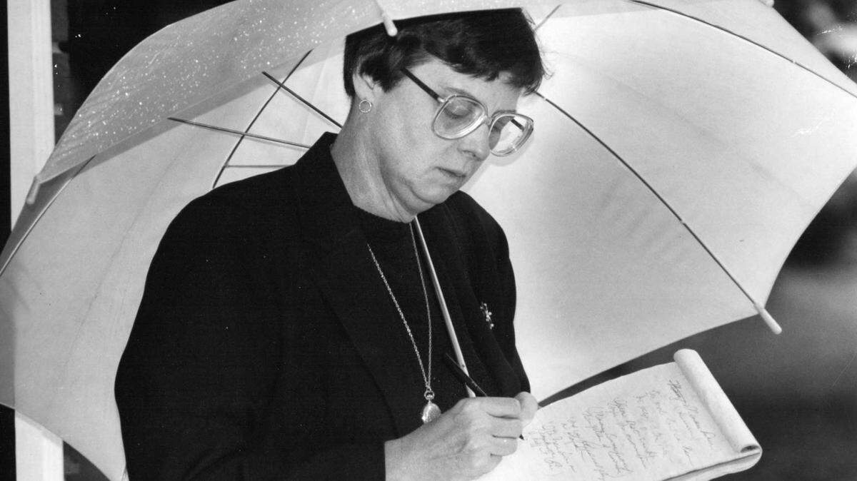 Former Raleigh Times and News & Observer reporter Treva Jones takes notes under an umbrella in this undated file photo. She died Friday, Jan. 18, 2019, at the age of 73.