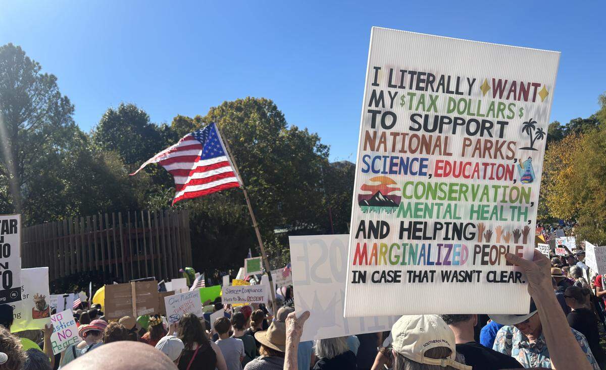 A protester holds up a sign about their tax dollars at the No Kings rally in Durham.