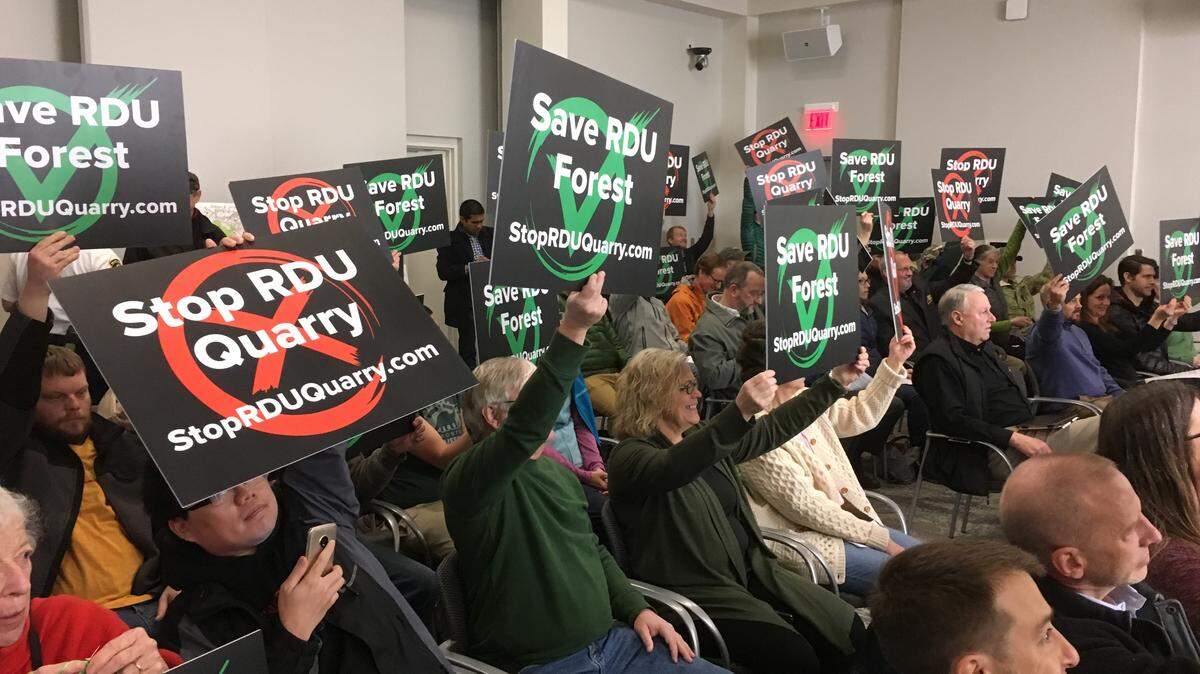 Members of the audience at the Raleigh-Durham Airport Authority’s meeting March 1, 2019, show their feelings before the board voted to lease 105 acres of airport land for a quarry.