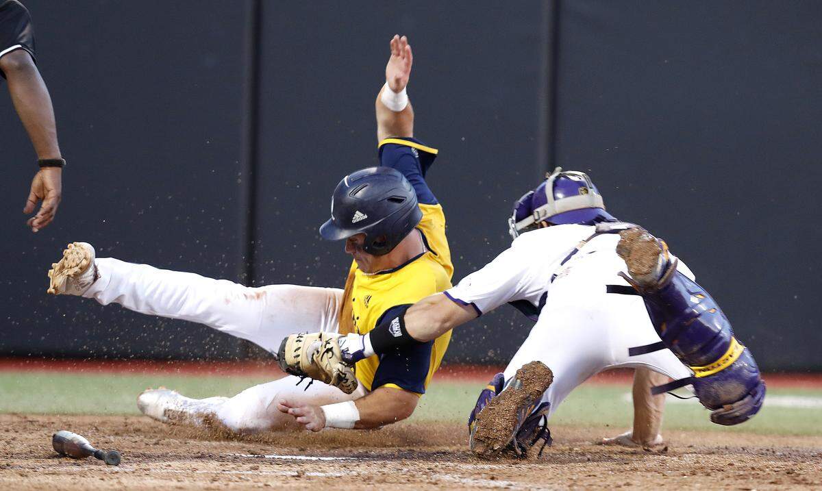 ECU’s Jake Washer (13) tags out Quinnipiac’s Evan Vulgamore (5) at home in the sixth inning during East Carolina University’s game against Quinnipiac in the Greenville Regional at Clark-LeClair Stadium in Greenville, N.C., Saturday, June 1, 2019.
