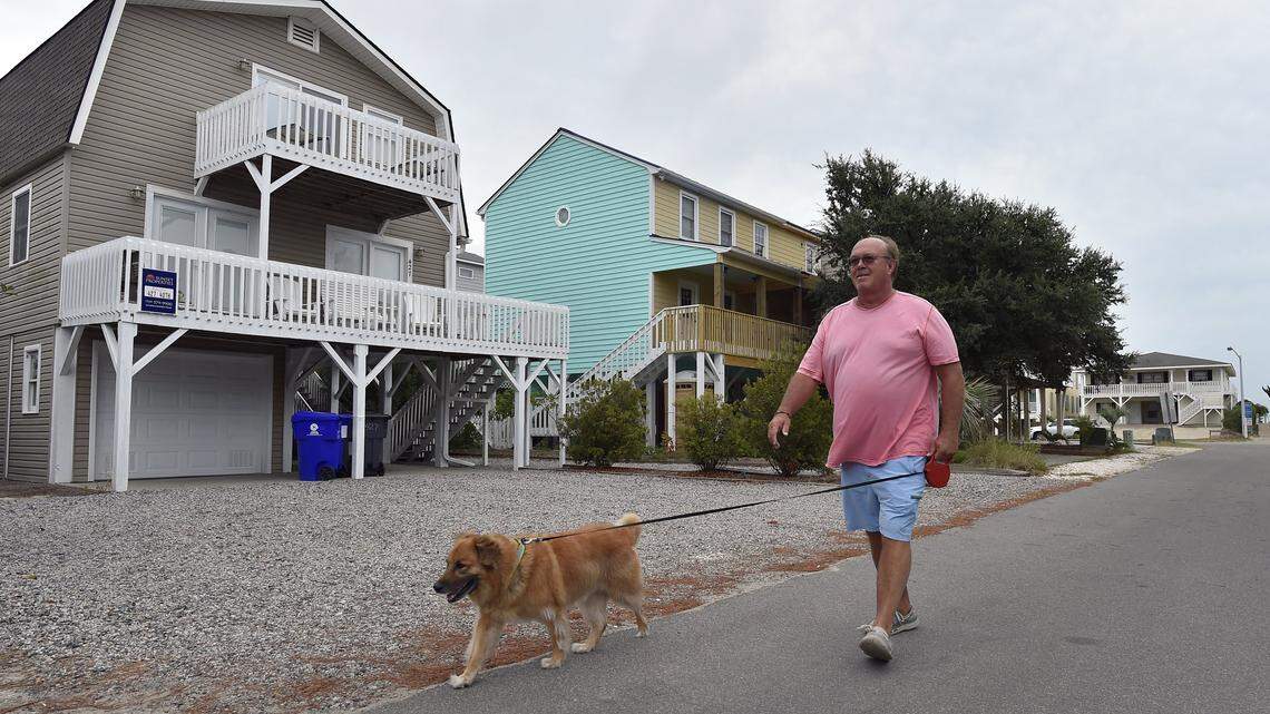 Mark Benton, Mayor pro tem of Sunset Beach, walks his dog, Joey, Thursday morning near his home on Sunset Beach. Hurricane Florence is predicted to hit the coast of North Carolina on Friday, but winds will pick up considerably beginning Thursday.