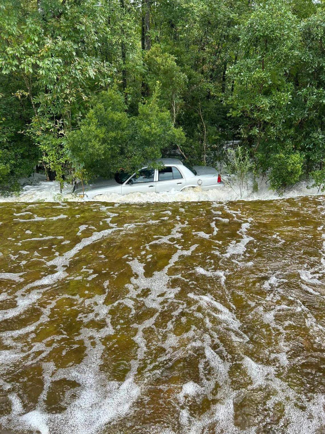Rushing flood waters push a car into the woods on US17 near NC 87 in Brunswick County, Monday, Sept. 16, 2024.