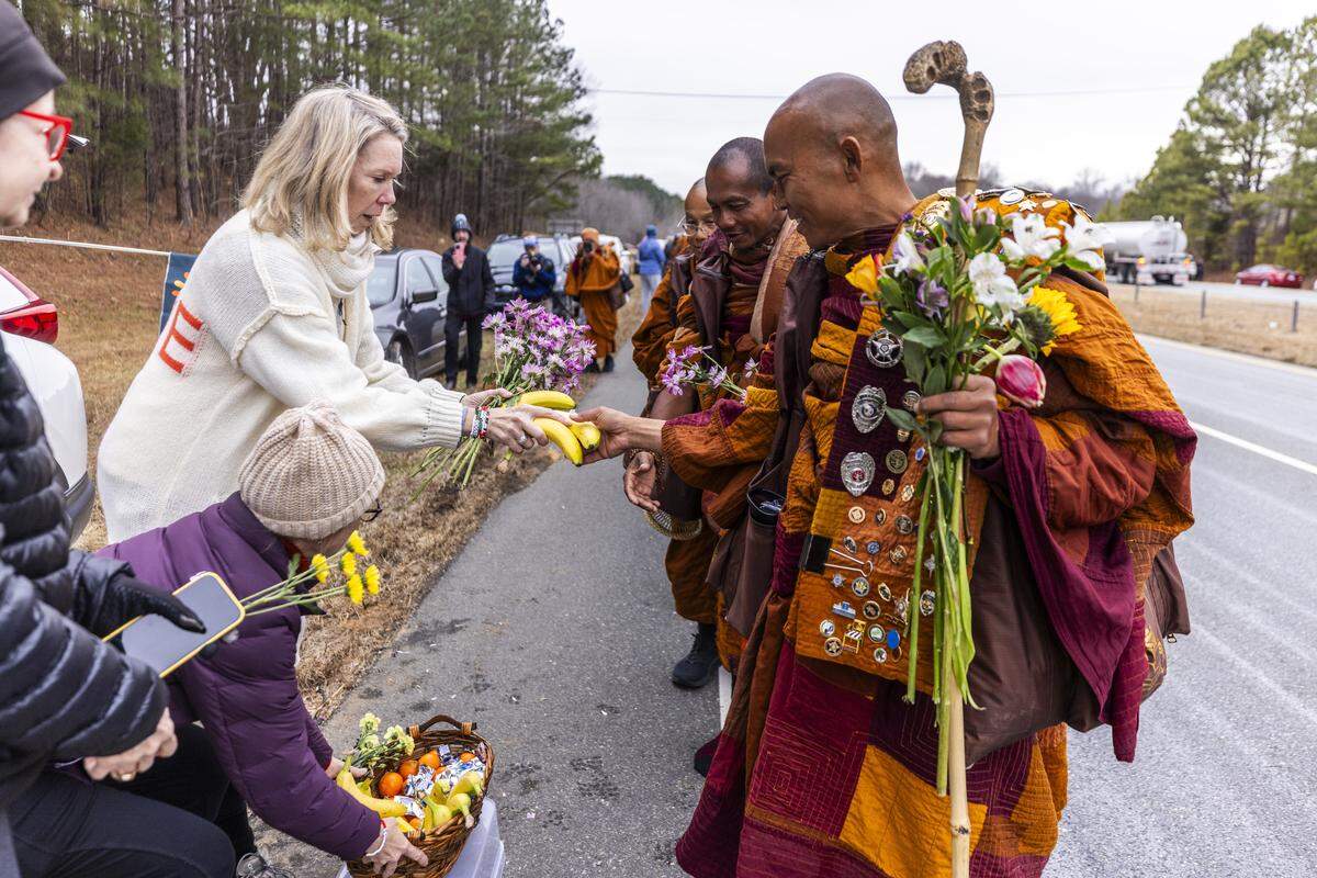 A small procession of Buddhist monks walks along U.S. Highway 64 west of Pittsboro on Thursday, Jan. 22, 2026, as hundreds of onlookers line the highway to welcome them. The monks are making a 2,300-mile pilgrimage from Texas to Washington, D.C., as part of the “Walk for Peace,” an effort to promote peace, compassion and national unity.