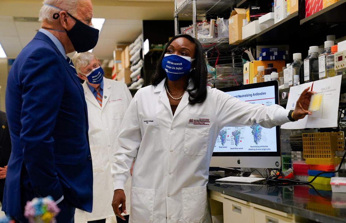 President Joe Biden listens as Kizzmekia Corbett, an immunologist with the Vaccine Research Center at the National Institutes of Health (NIH), right, speaks during a visit at the Viral Pathogenesis Laboratory at the NIH on Feb. 11, in Bethesda, Md. NIH Director Francis Collins is second from left.
