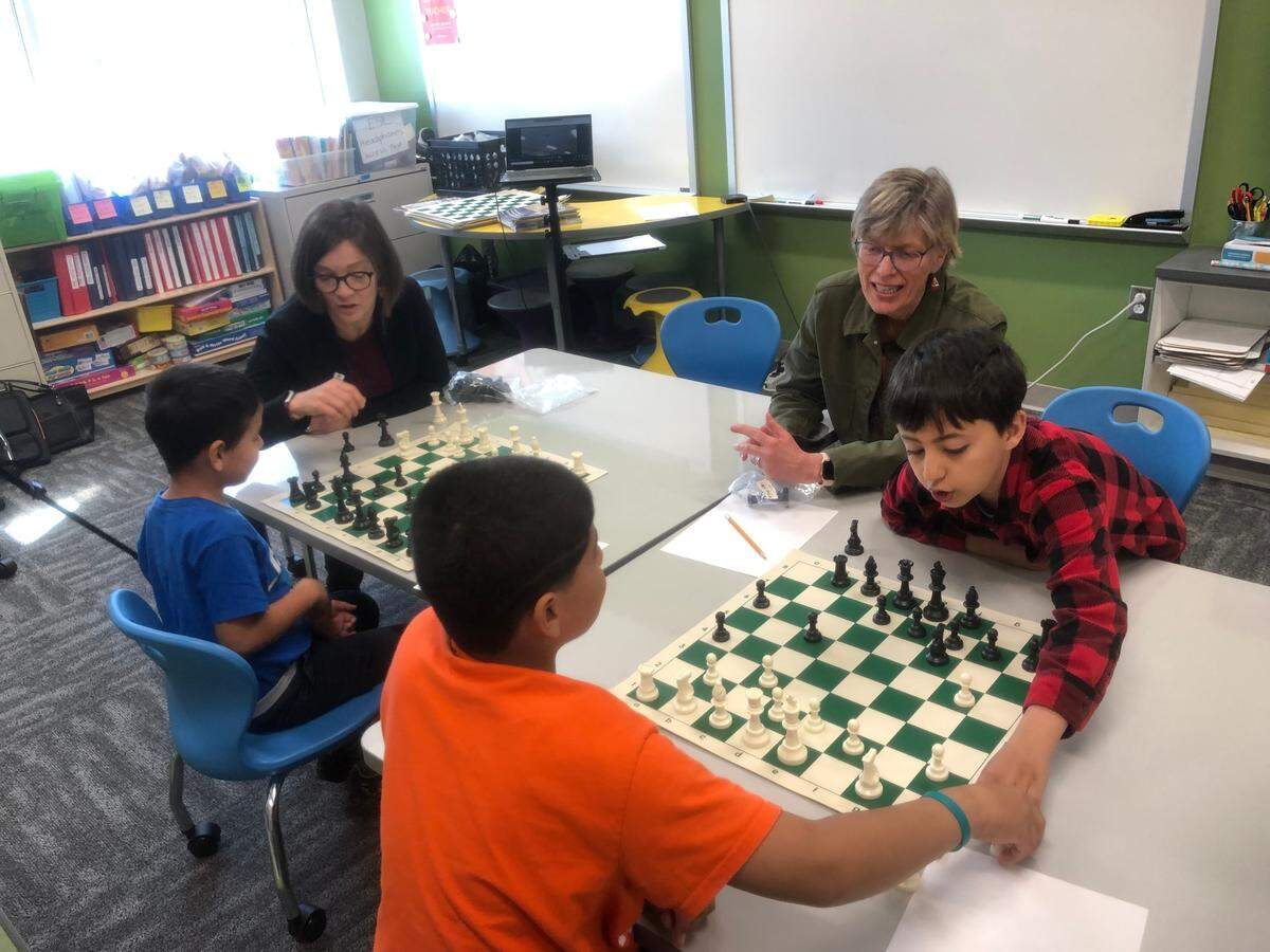 Afghan refugee students at Stough Elementary School learn how to play chess on April 1, 2022 in Raleigh, N.C. Pictured clockwise are U.S Chess Federation executive director Carol Meyer, Stough ESL teacher Cindy Linton and students Ahmad, Sadiqullah and Qudratullah.