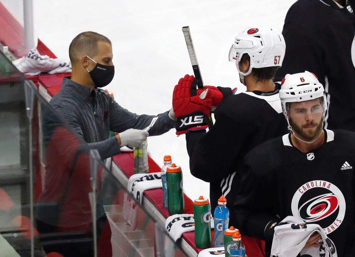 Carolina Hurricanes equipment manager Jorge Alves, left, helps Trevor van Riemsdyk (57) during the Carolina Hurricanes’ on-ice workouts at PNC Arena in Raleigh, N.C., Monday, July 13, 2020.