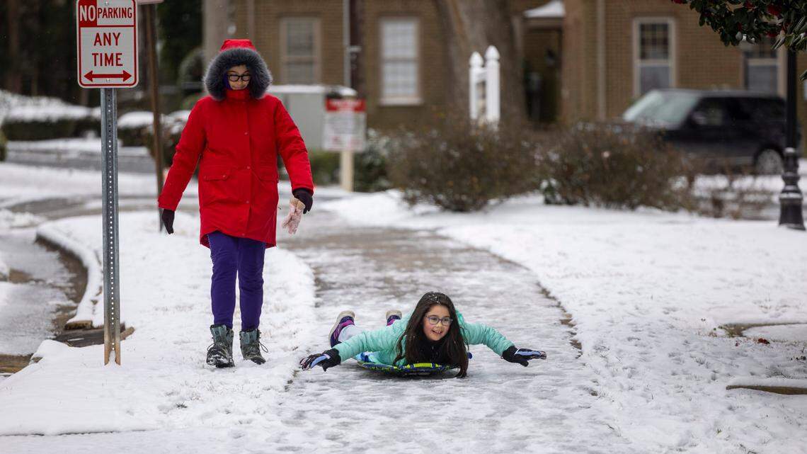 Mirabel Schafrath-Craig, 10, slides along the sidewalk on Washington Street in Raleigh while walking with her mother Adalia Schafrath-Craig on Thursday, Feb. 20, 2025. Several inches of snow fell in the area on Wednesday with temperatures dipping to 25 degrees.