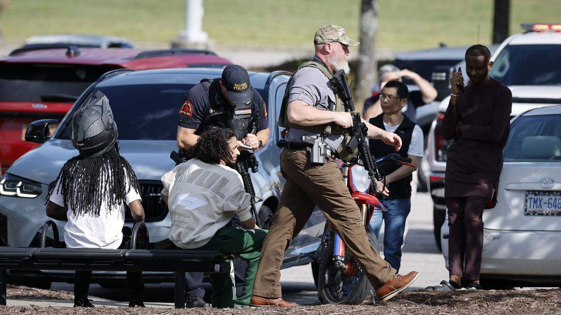 A Raleigh police officer interviews people as another officer carrying a long gun walks by following reports of a shooting at Triangle Town Center in Raleigh on April 17.