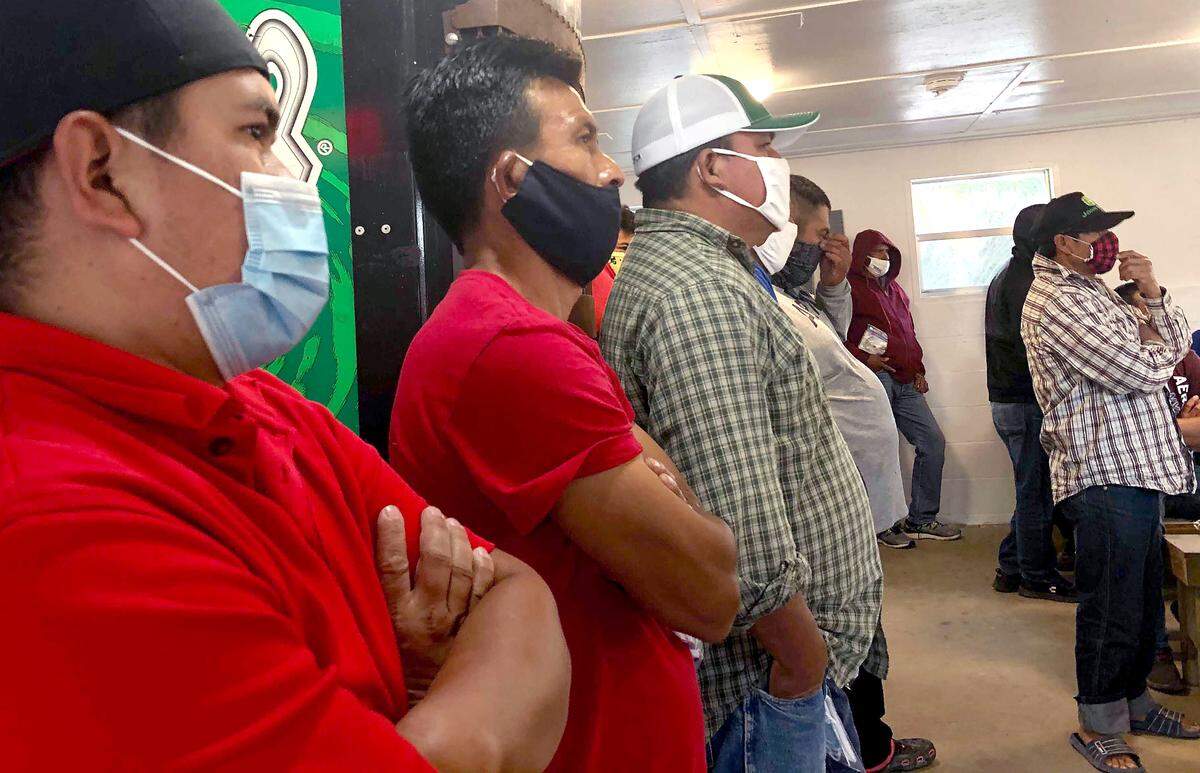 Seasonal migrant farmworkers with temproary H-2A work visas listen to outreach workers from The N.C. Farmworkers’ Project provide education the COVID-19 vaccine during a visit to their housing in Four Oaks, N.C on Sunday, April 4, 2021.