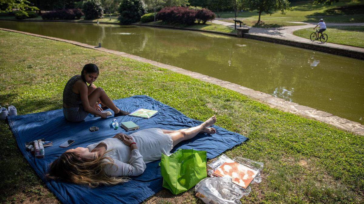 Aniyah Buckner, left, and Stella Ervin seek relief from the heat under the shade of the trees at Freedom Park in Charlotte, N.C., on May 24, 2021. The first heat wave of 2022 is expected to “engulf” the region next week, the NWS warned.