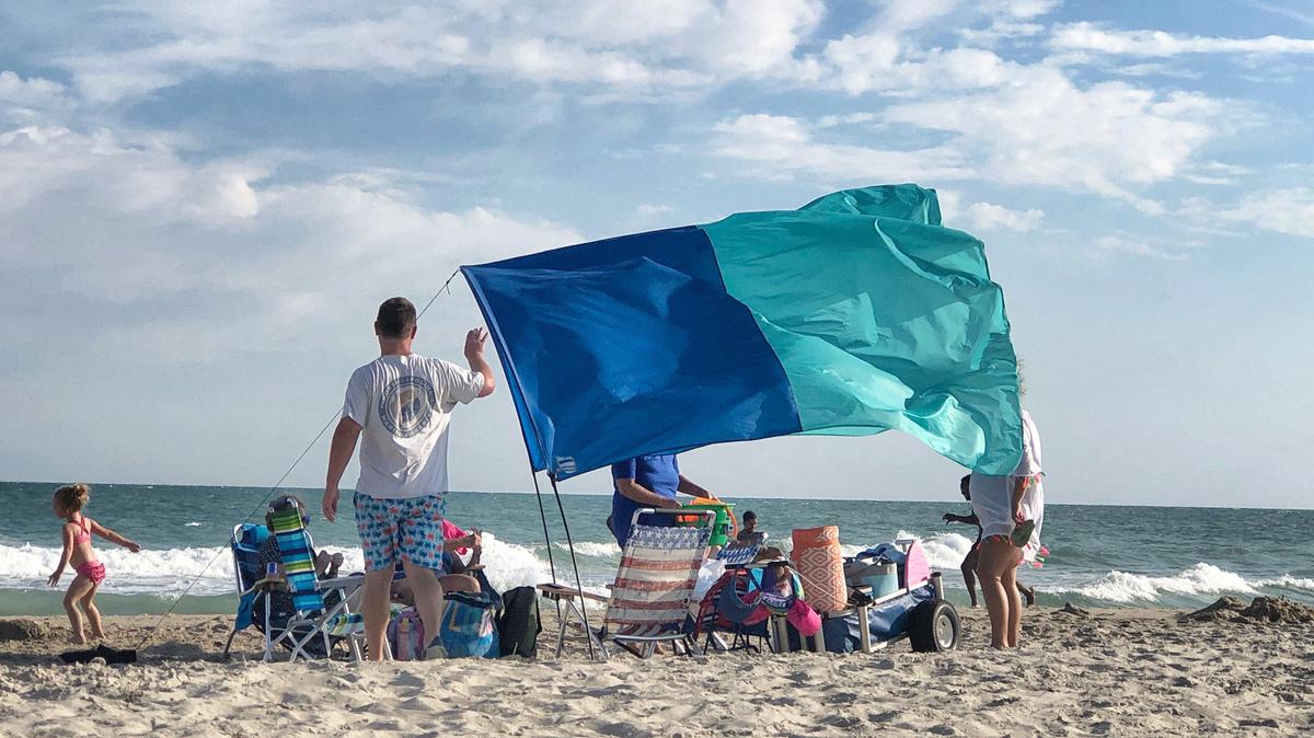 A family enjoys relief from the sun under a Shibumi Shade at Emerald Isle in July.